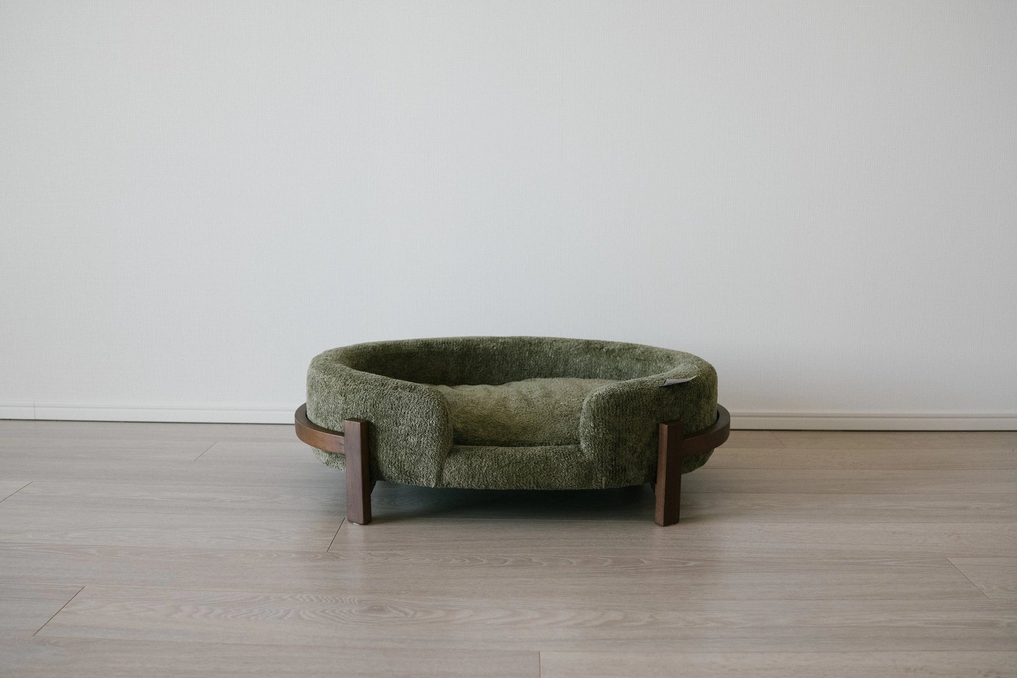 The Chic Henley Dog Bed in Eucalyptus, straight-on view on its curved wood-veneer frame
